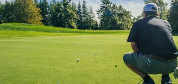 A golfer crouches down on the putting green at The Links at Crowbush Cove.