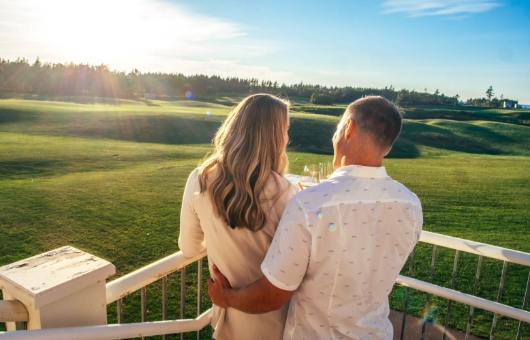 A couple embrace and enjoy the view of a PEI golf course.